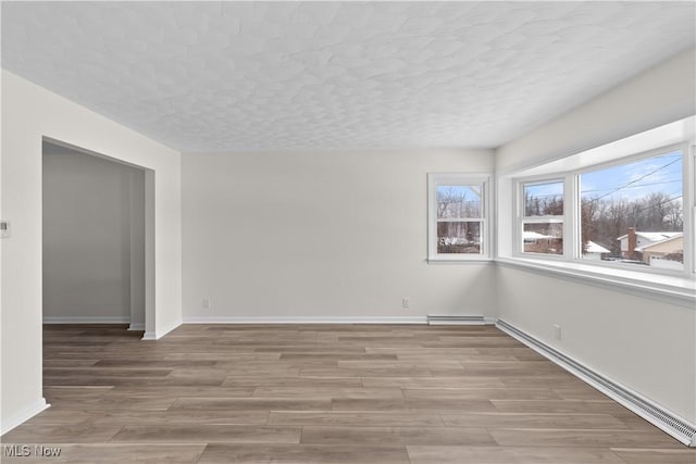 empty room featuring a textured ceiling and light hardwood / wood-style flooring