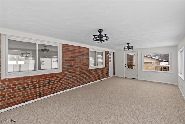 unfurnished living room featuring carpet flooring, ceiling fan, and brick wall