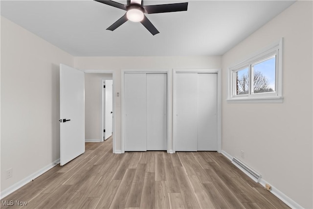 unfurnished bedroom featuring ceiling fan, light hardwood / wood-style flooring, and two closets