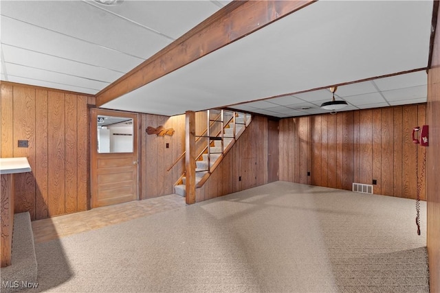 basement with wooden walls and a drop ceiling