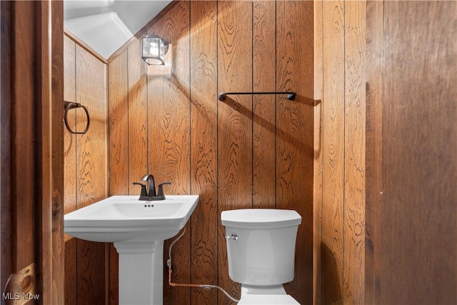 bathroom with toilet and wood walls