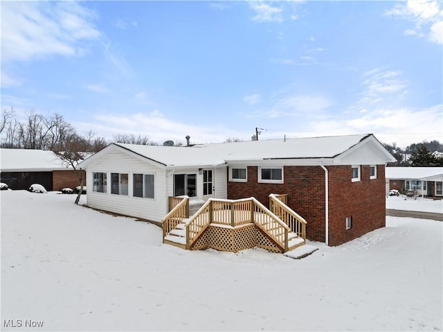 snow covered back of property featuring a wooden deck