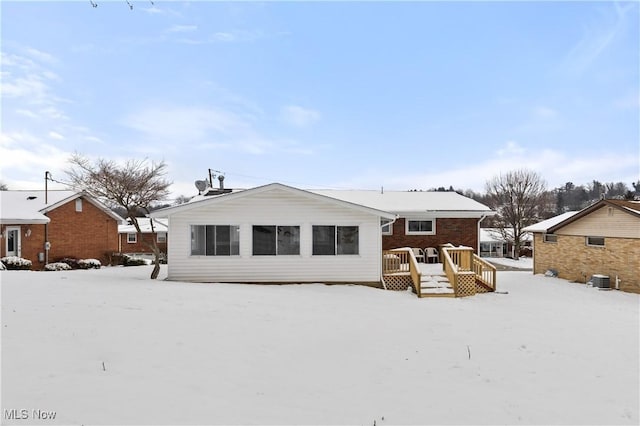 snow covered rear of property with a deck