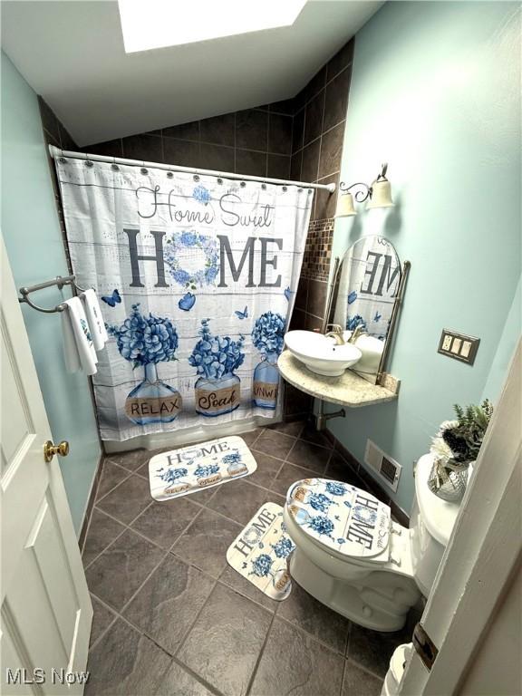 bathroom with a shower with curtain, sink, lofted ceiling, and toilet