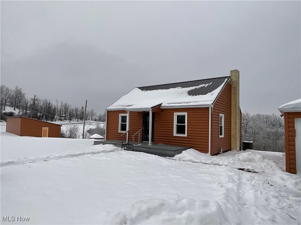 snow covered house featuring cooling unit