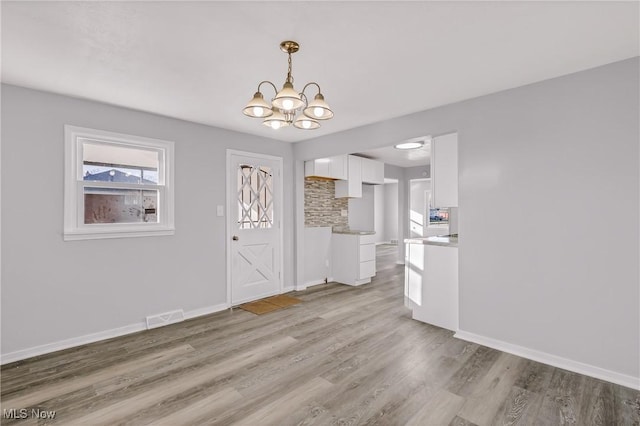 unfurnished dining area with light hardwood / wood-style floors and a chandelier