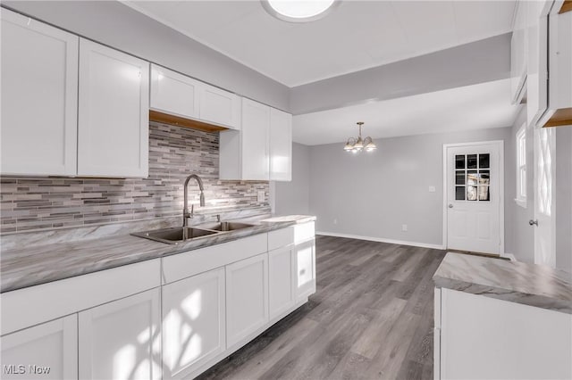 kitchen featuring backsplash, decorative light fixtures, white cabinetry, and sink