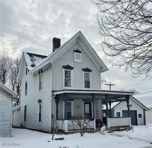 view of front of home featuring a garage, covered porch, and an outbuilding