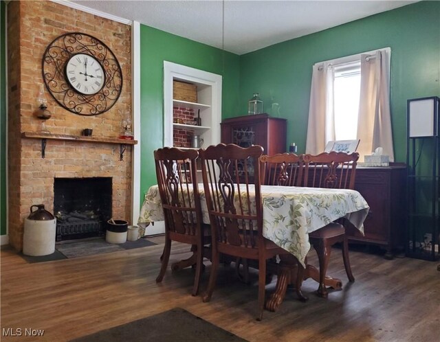 dining area featuring hardwood / wood-style floors, built in features, and a fireplace