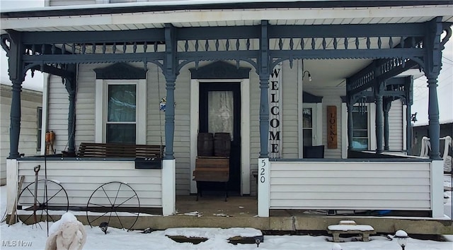 snow covered property entrance featuring a porch