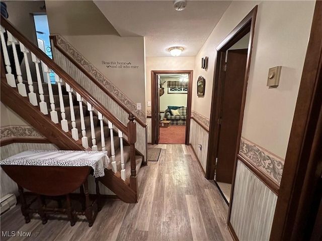 hall with hardwood / wood-style floors, a textured ceiling, and baseboard heating