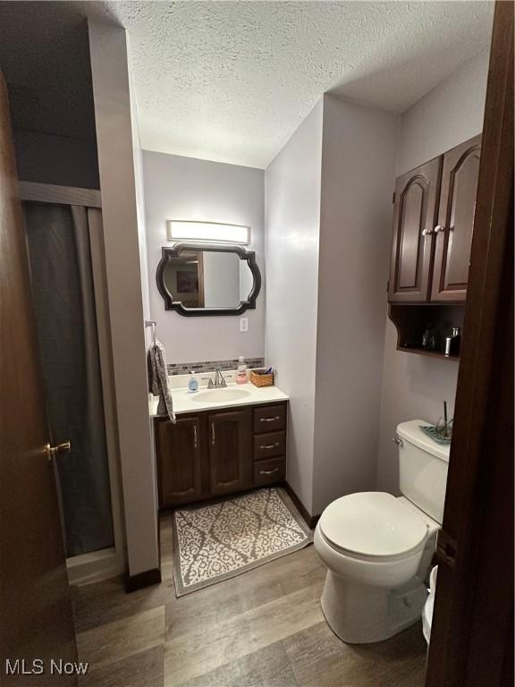 bathroom featuring vanity, wood-type flooring, a textured ceiling, and toilet