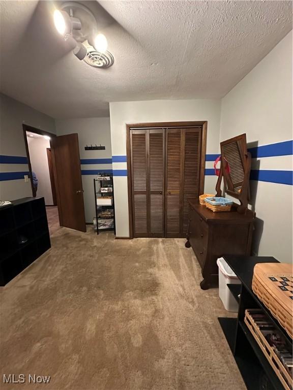 bedroom with carpet flooring, a textured ceiling, and a closet