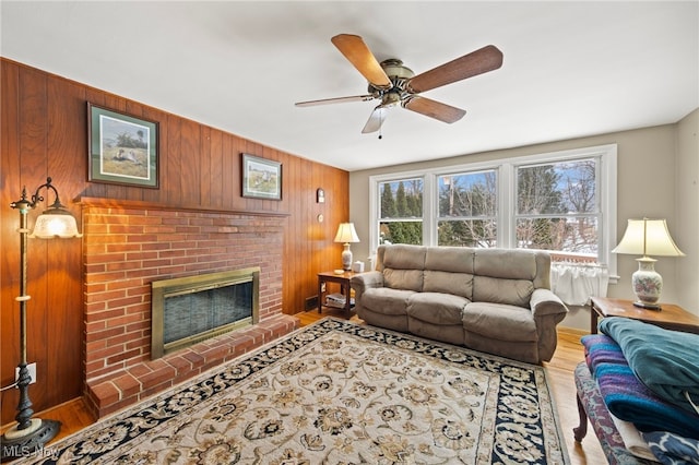 living room featuring wood walls, a fireplace, ceiling fan, and wood-type flooring