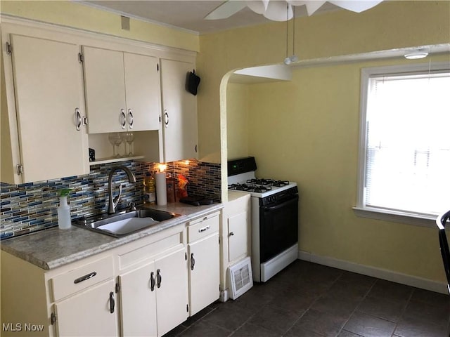 kitchen with tasteful backsplash, white gas range, white cabinetry, and sink