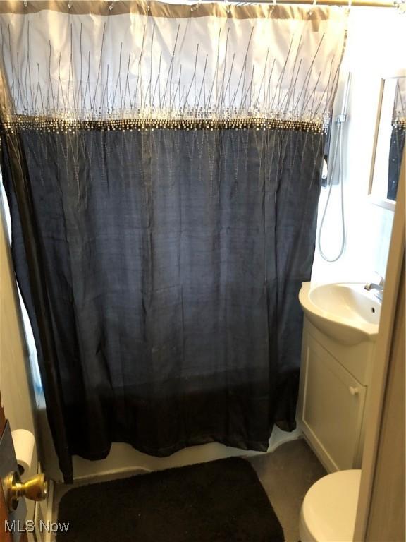 bathroom featuring vanity, curtained shower, and toilet