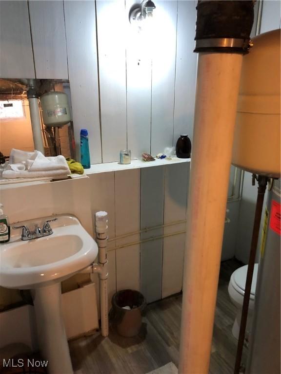 bathroom featuring water heater, sink, wood-type flooring, and toilet