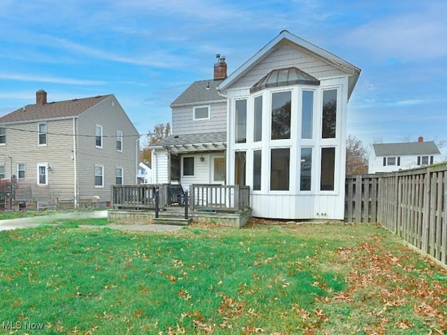 back of house featuring a lawn and a deck