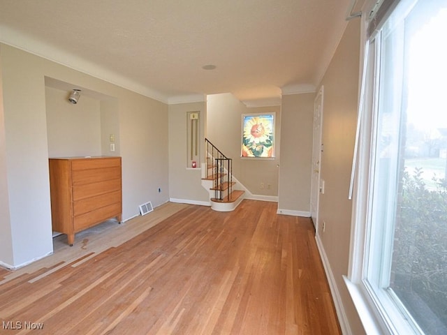 empty room featuring light wood-type flooring and ornamental molding