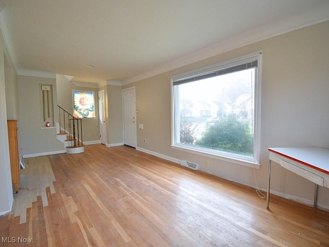 unfurnished living room with crown molding and light wood-type flooring