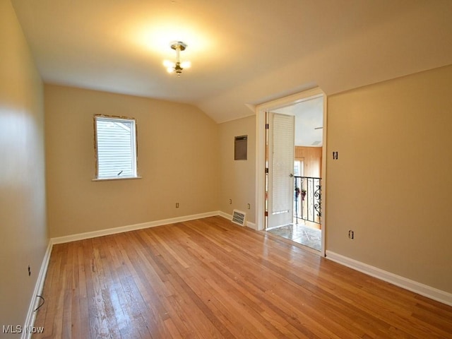 spare room with light hardwood / wood-style floors and lofted ceiling