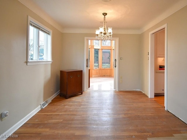 unfurnished dining area featuring light wood-type flooring and a notable chandelier