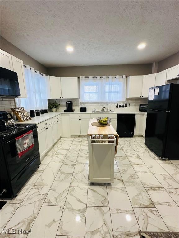 kitchen with backsplash, white cabinets, black appliances, and a textured ceiling