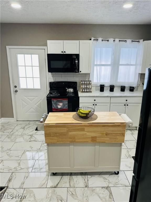 kitchen featuring white cabinets, a textured ceiling, butcher block countertops, and black appliances