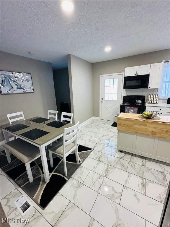 kitchen with wooden counters, backsplash, a textured ceiling, black appliances, and white cabinets