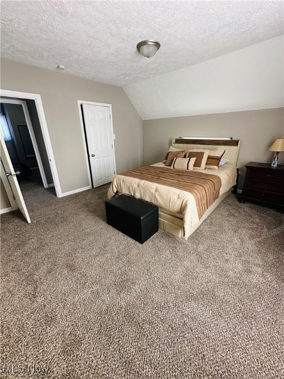 bedroom featuring vaulted ceiling, carpet floors, and a textured ceiling