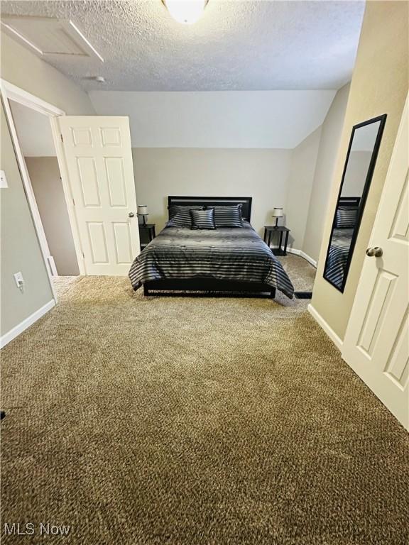 carpeted bedroom featuring a textured ceiling and vaulted ceiling