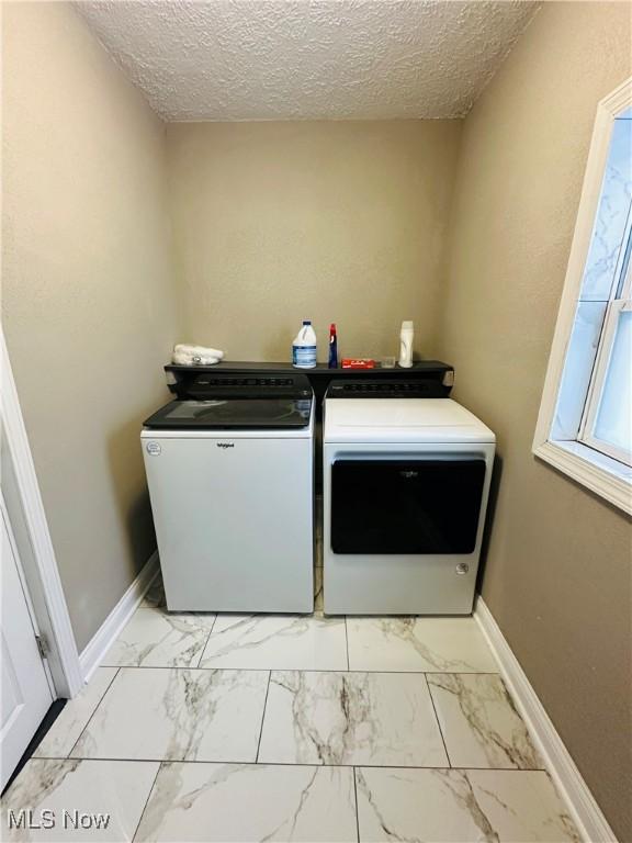 clothes washing area featuring washer and dryer and a textured ceiling