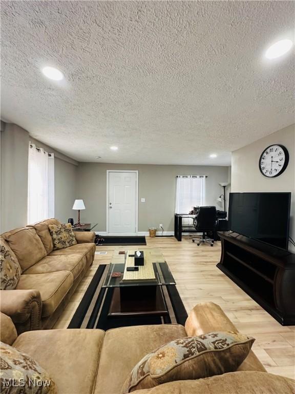 living room with a textured ceiling and light hardwood / wood-style flooring