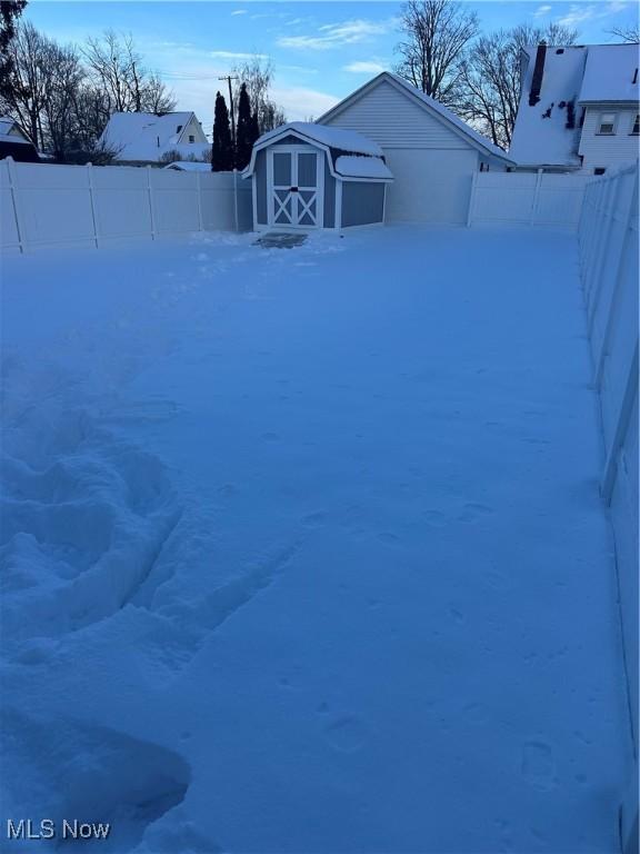 snowy yard with a storage shed