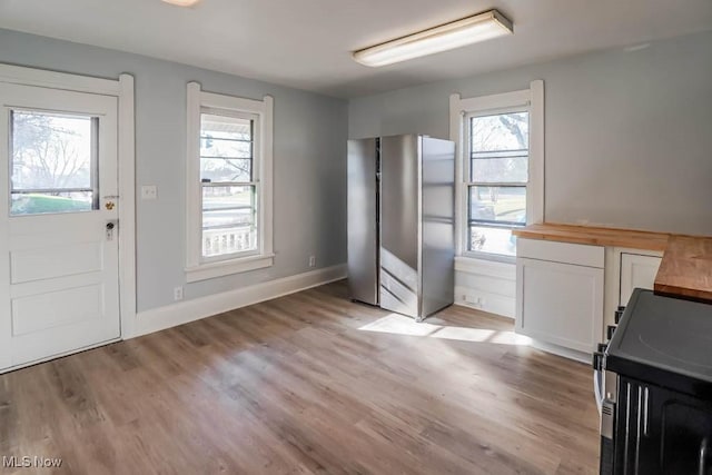 interior space featuring stainless steel refrigerator, butcher block counters, plenty of natural light, white cabinets, and range