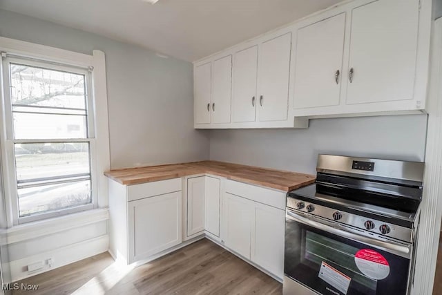 kitchen featuring white cabinetry, stainless steel range, light wood-type flooring, and wood counters