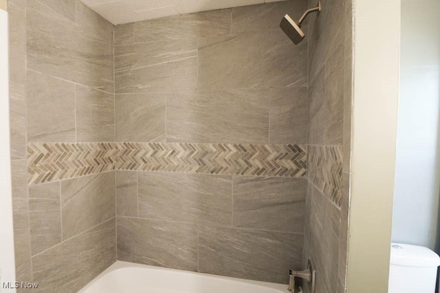 bathroom with tiled shower / bath combo and toilet