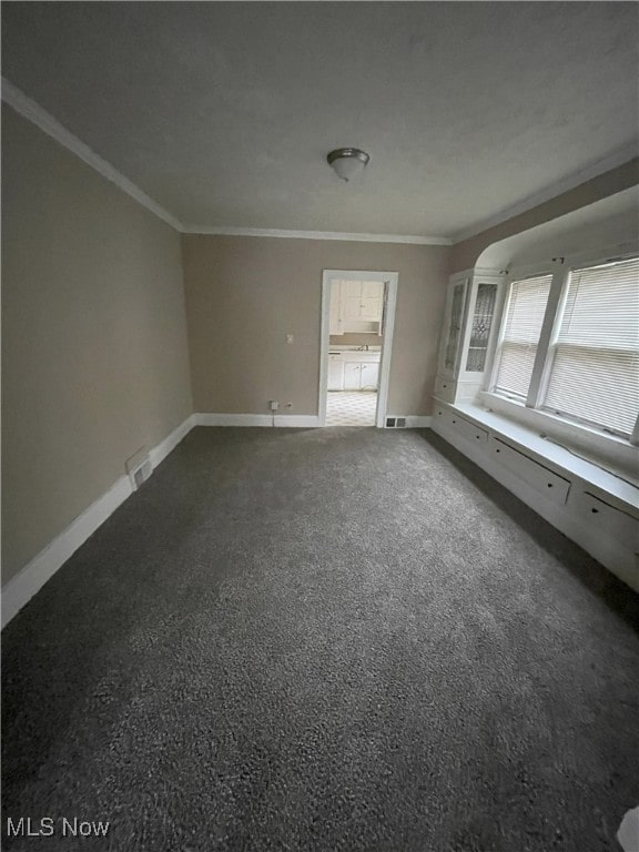 unfurnished room with dark colored carpet and ornamental molding