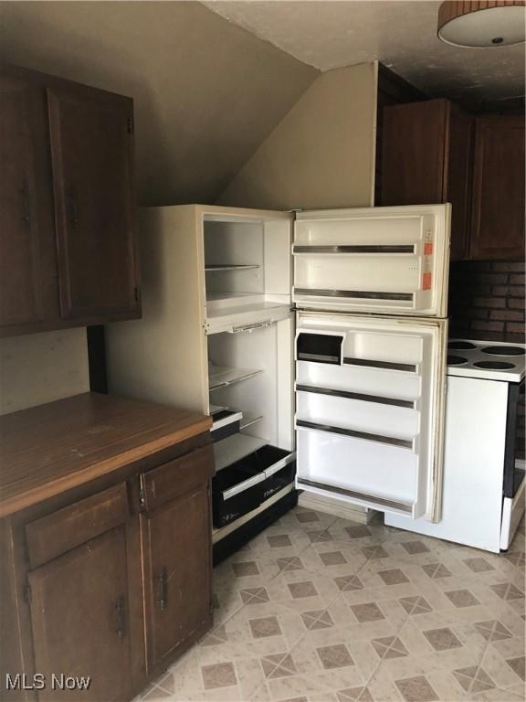 kitchen with dark brown cabinetry, lofted ceiling, and white electric range