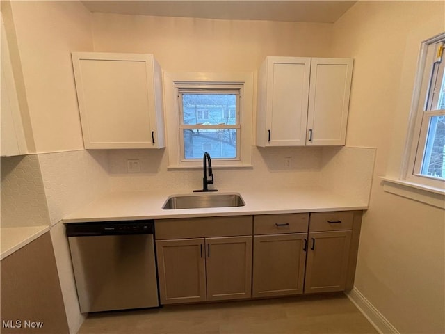 kitchen featuring dishwasher, white cabinetry, sink, and a wealth of natural light