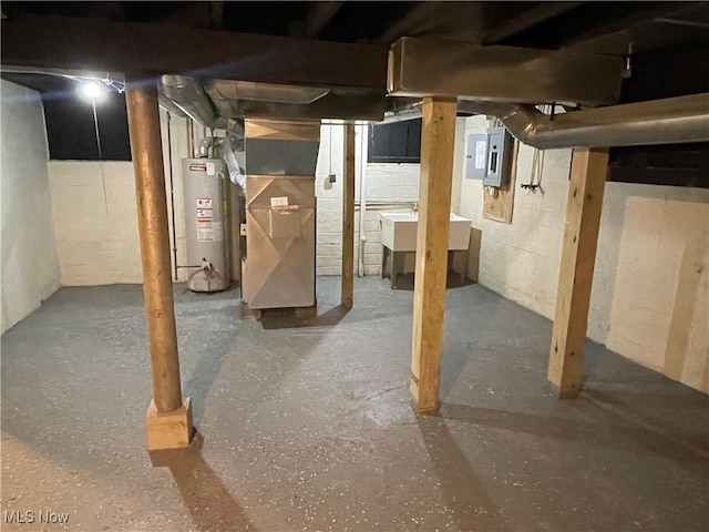 basement featuring sink, electric panel, heating unit, and water heater