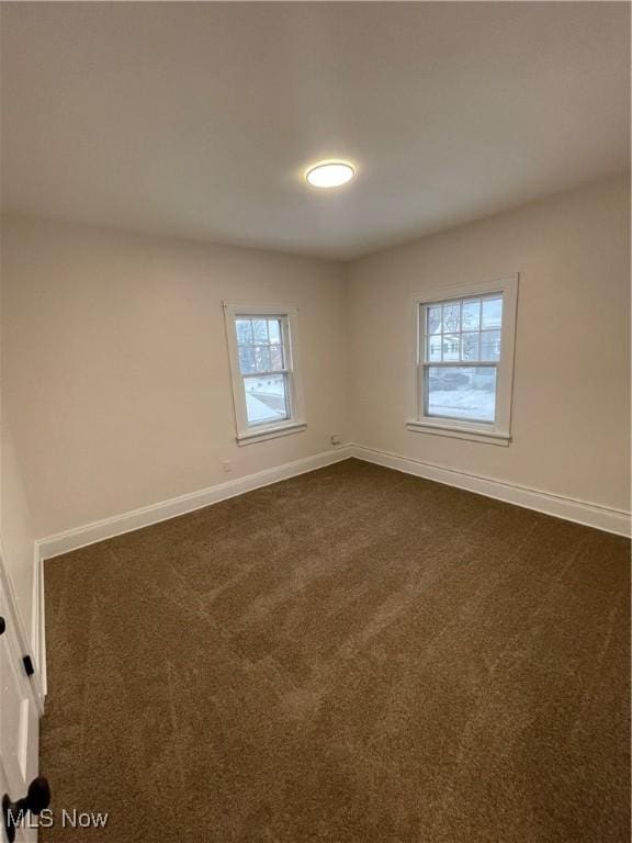 spare room with dark carpet