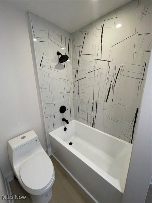 bathroom with hardwood / wood-style floors, toilet, and tiled shower / bath