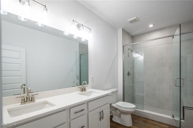 bathroom with toilet, a sink, a stall shower, and wood finished floors