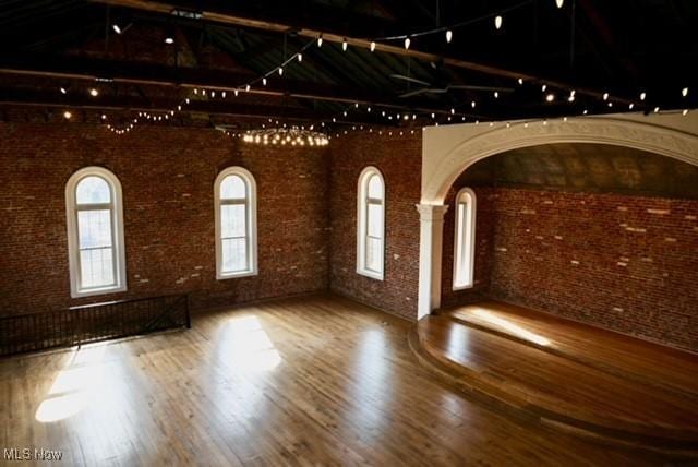 unfurnished room featuring hardwood / wood-style floors and brick wall