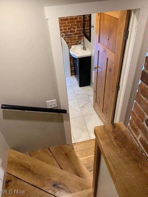 stairway featuring sink and brick wall