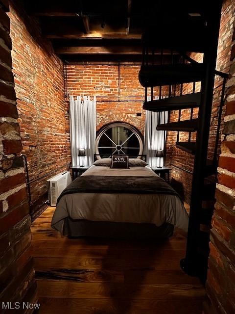 bedroom with beam ceiling and hardwood / wood-style floors