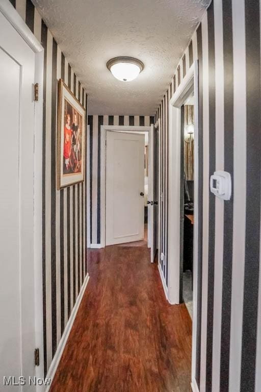 hallway with dark hardwood / wood-style flooring and a textured ceiling