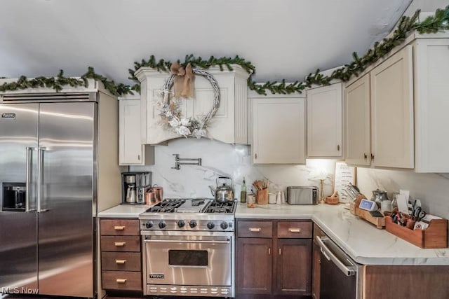 kitchen featuring white cabinets, tasteful backsplash, high end appliances, and custom exhaust hood