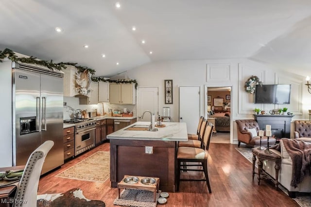 kitchen with high quality appliances, sink, vaulted ceiling, and hardwood / wood-style flooring